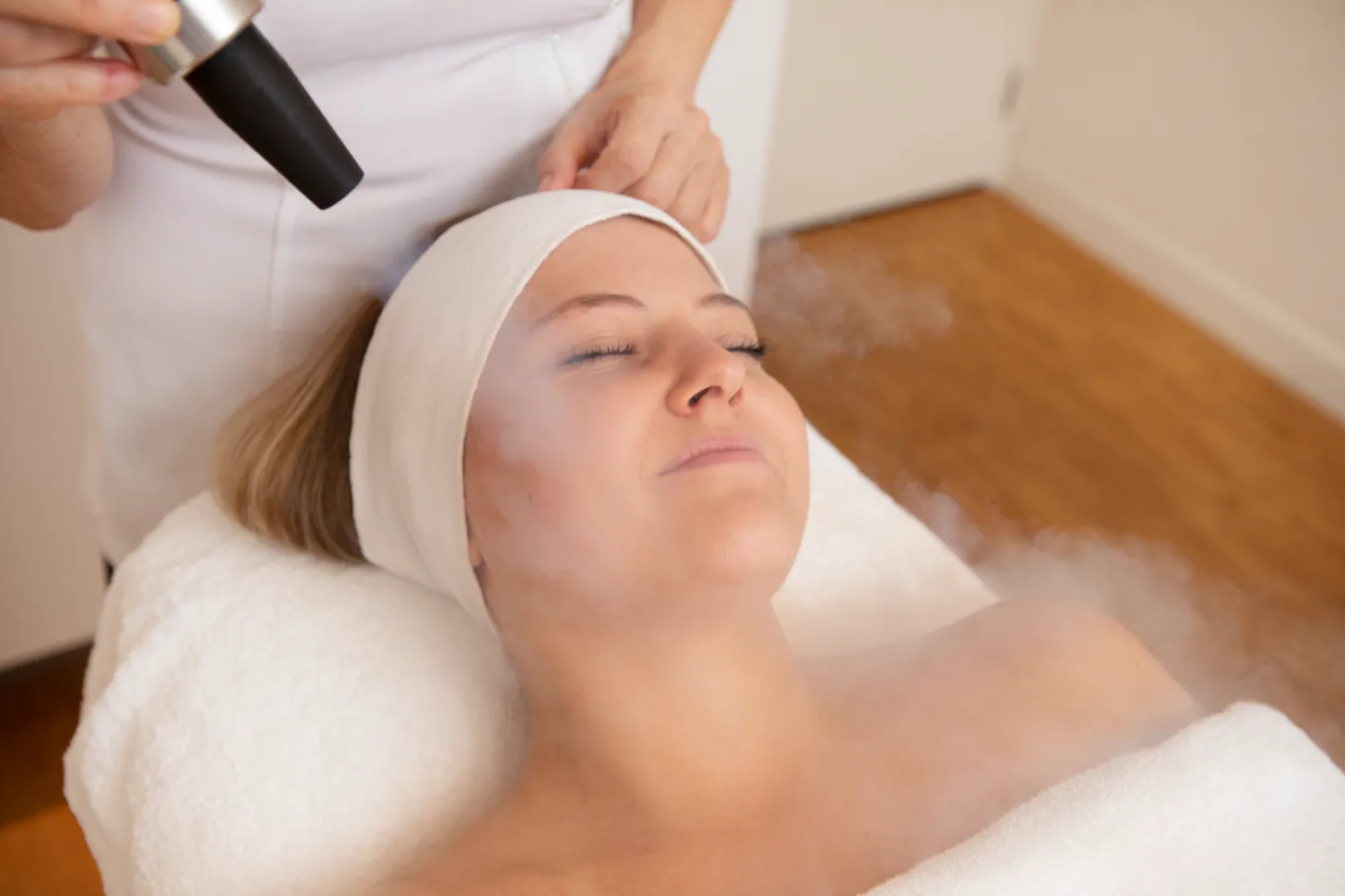 Schoonheidsspecialist behandelt de huid van patiënt op ligstoel met stoom bij Skin Solutions in Hoorn